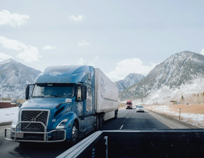 a blue semi truck driving down a mountain road
